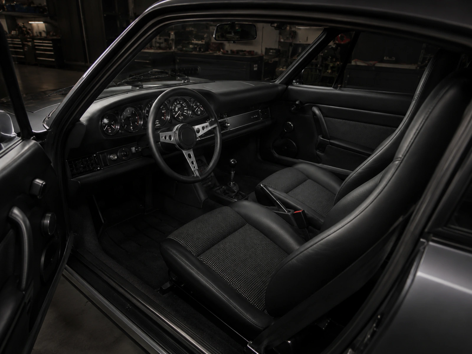 Dark Black Index cabin with analogue gauges, black leather and restrained aluminium controls
